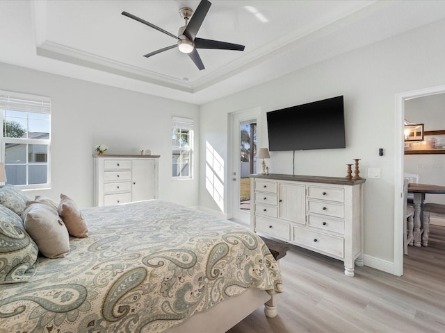 bedroom featuring a tray ceiling, ceiling fan, light hardwood / wood-style flooring, and ornamental molding