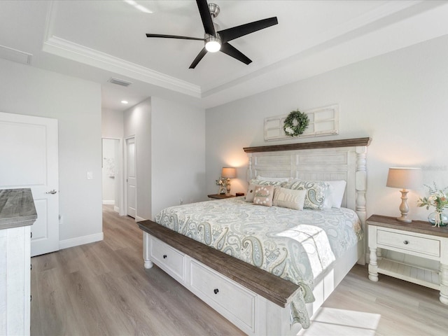 bedroom featuring ceiling fan, light wood-type flooring, and a tray ceiling