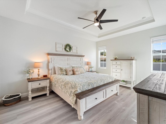 bedroom featuring ceiling fan, light hardwood / wood-style floors, and a raised ceiling