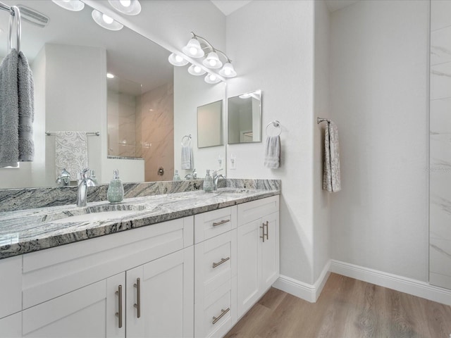 bathroom with hardwood / wood-style floors, vanity, and a tile shower