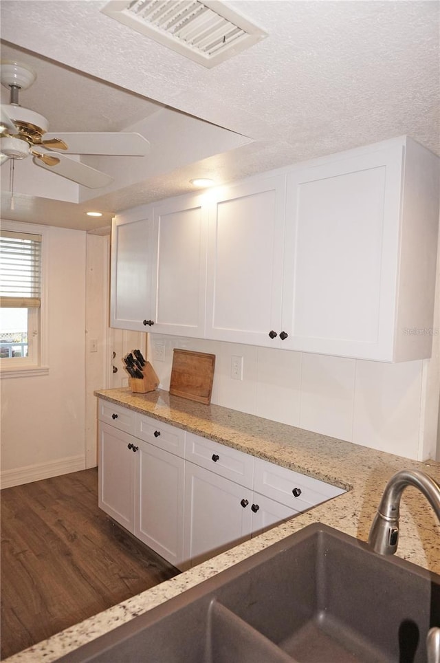 kitchen with light stone counters, a textured ceiling, ceiling fan, white cabinets, and dark hardwood / wood-style floors