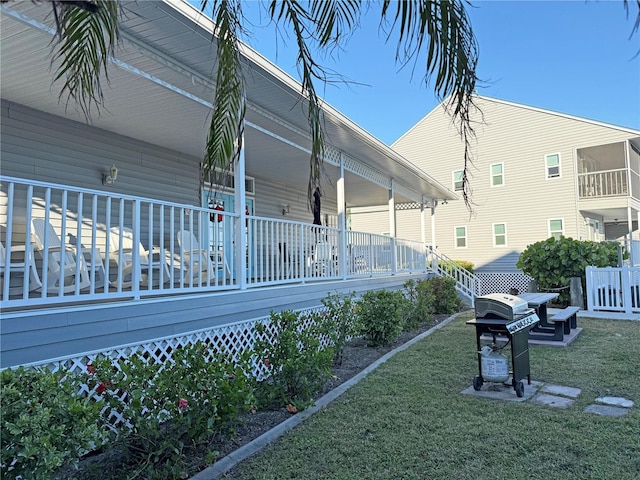 view of side of home with covered porch and a yard