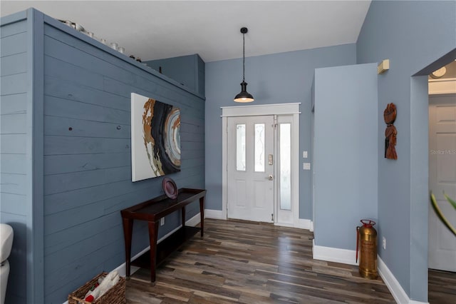 foyer entrance with wood walls and dark wood-type flooring