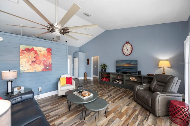 living room with wood-type flooring, vaulted ceiling, ceiling fan, and wood walls