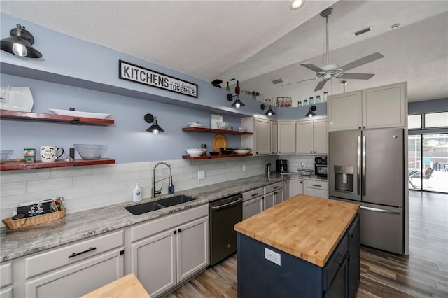 kitchen featuring ceiling fan, sink, stainless steel appliances, wooden counters, and a kitchen island