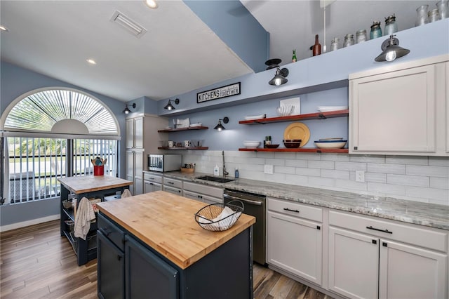 kitchen with butcher block counters, white cabinetry, a center island, and stainless steel appliances