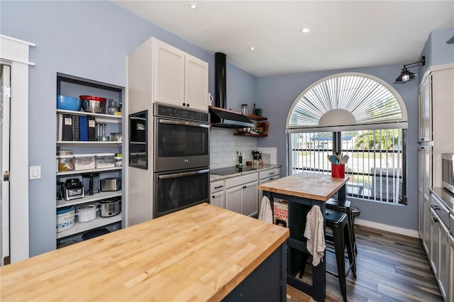 kitchen with dark wood-type flooring, black electric stovetop, stainless steel double oven, tasteful backsplash, and white cabinetry