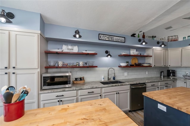 kitchen featuring wooden counters, sink, a textured ceiling, dark hardwood / wood-style flooring, and stainless steel appliances