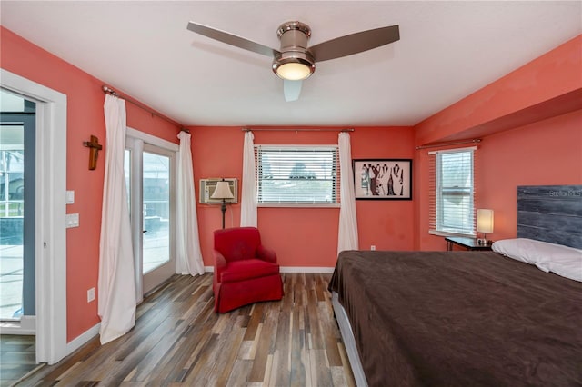 bedroom featuring multiple windows, hardwood / wood-style floors, a wall unit AC, and ceiling fan