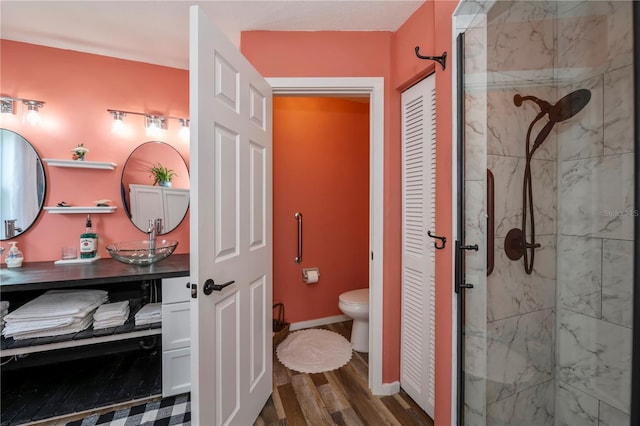 bathroom with hardwood / wood-style floors, vanity, toilet, and a tile shower