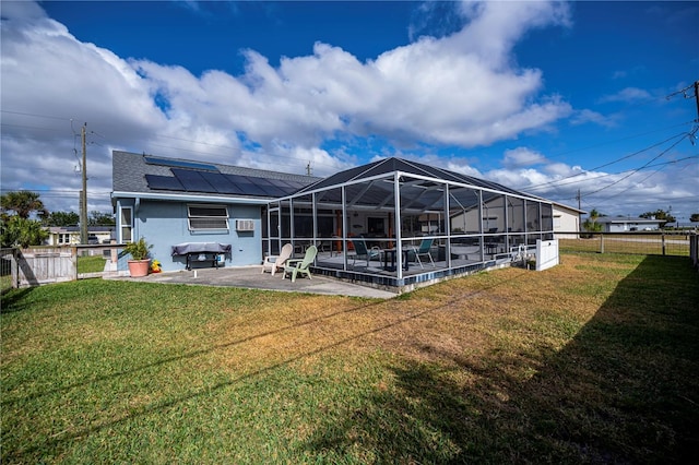 back of house with solar panels, a lanai, a yard, and a patio