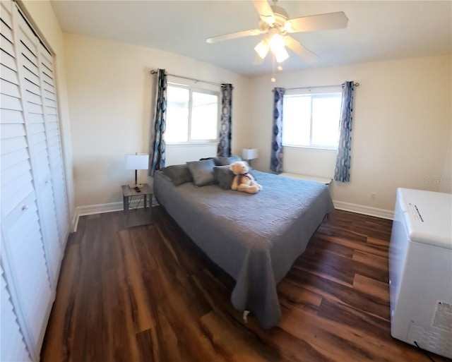 bedroom featuring multiple windows, a closet, dark hardwood / wood-style floors, and ceiling fan