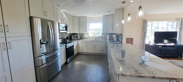 kitchen featuring a healthy amount of sunlight, hanging light fixtures, appliances with stainless steel finishes, and tasteful backsplash