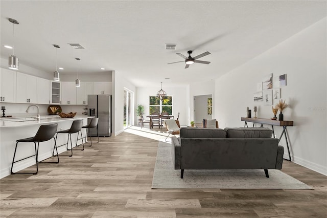 living room featuring ceiling fan, light wood-type flooring, and sink