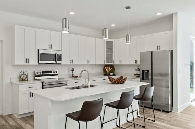 kitchen with sink, stainless steel appliances, light hardwood / wood-style flooring, a center island with sink, and white cabinets