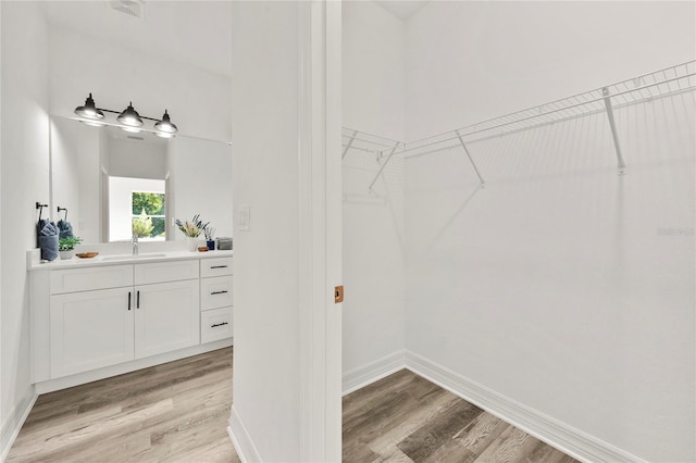 walk in closet featuring sink and light hardwood / wood-style floors