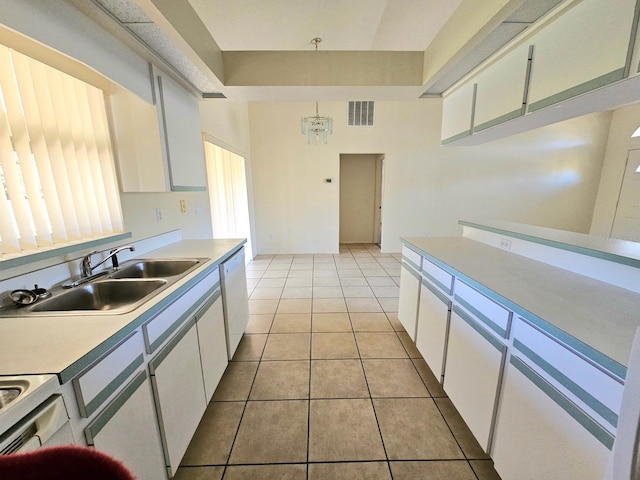 kitchen with sink, white cabinets, decorative light fixtures, and light tile patterned floors