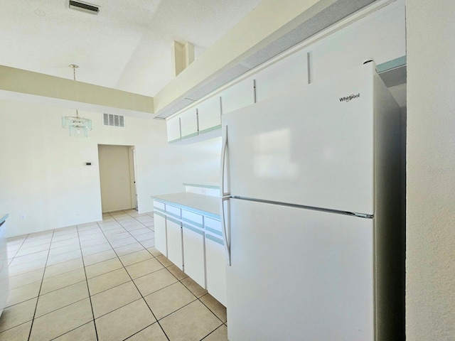 kitchen featuring white refrigerator, white cabinetry, hanging light fixtures, and a notable chandelier