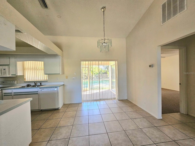 kitchen with light tile patterned floors, high vaulted ceiling, decorative light fixtures, white appliances, and white cabinets