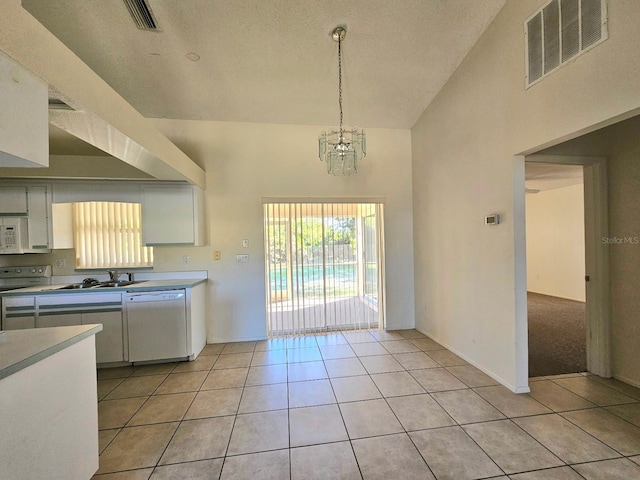 kitchen featuring white appliances, decorative light fixtures, high vaulted ceiling, white cabinetry, and light tile patterned flooring