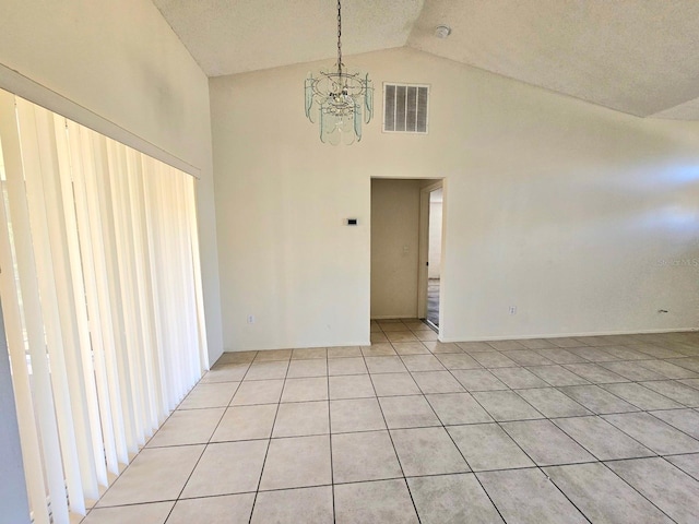 tiled empty room featuring a textured ceiling, high vaulted ceiling, and a notable chandelier