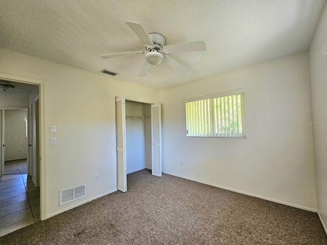 unfurnished bedroom with carpet flooring, ceiling fan, a closet, and a textured ceiling