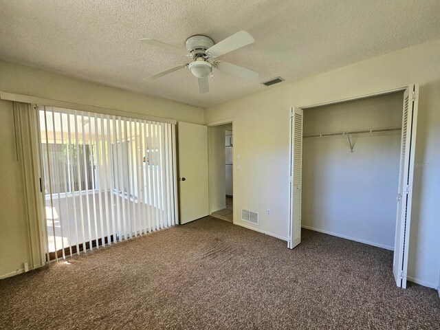 unfurnished bedroom featuring dark colored carpet, ceiling fan, a textured ceiling, and a closet