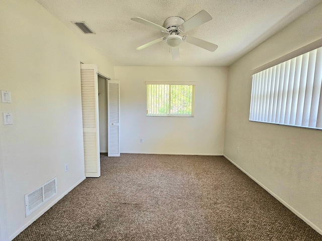 carpeted spare room featuring a textured ceiling and ceiling fan