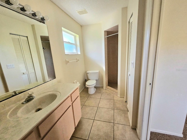 bathroom featuring walk in shower, vanity, a textured ceiling, tile patterned flooring, and toilet