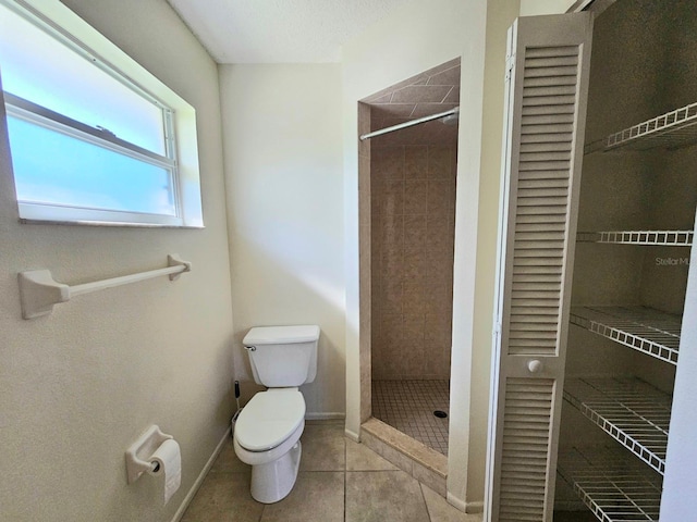 bathroom with tile patterned floors, toilet, and a tile shower