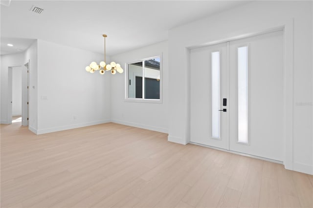 foyer with plenty of natural light, light hardwood / wood-style floors, and an inviting chandelier