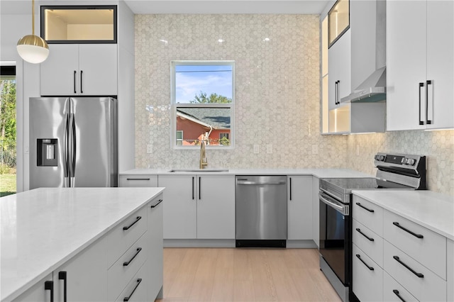 kitchen with sink, white cabinets, stainless steel appliances, and decorative light fixtures