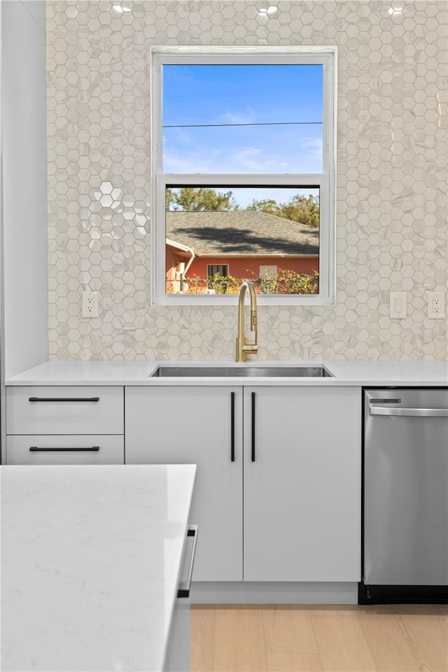 kitchen with light hardwood / wood-style flooring, stainless steel dishwasher, plenty of natural light, and sink