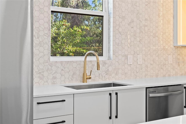 kitchen featuring tasteful backsplash, dishwasher, white cabinets, and sink