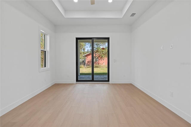 spare room with a raised ceiling and light hardwood / wood-style flooring