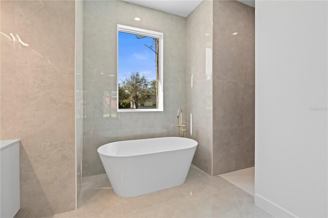 bathroom with tile patterned flooring, a washtub, and tile walls