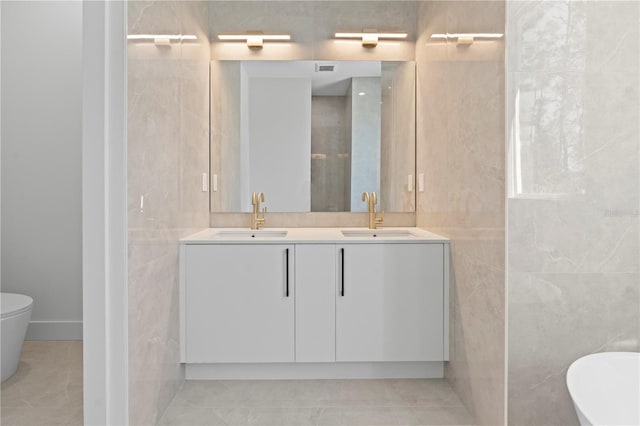 bathroom featuring tile patterned flooring, vanity, and tile walls