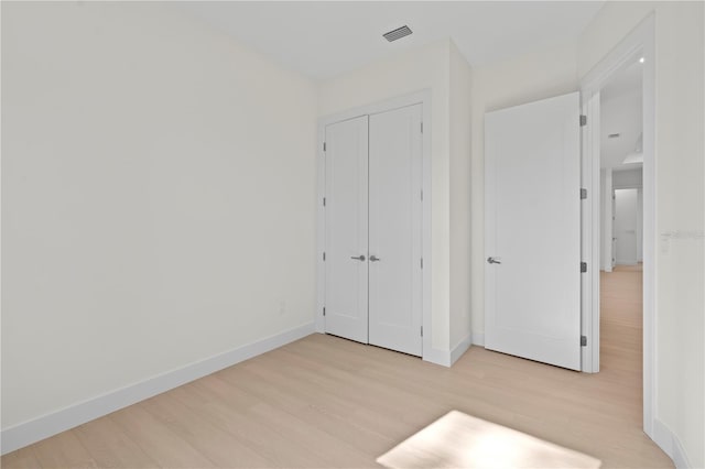 unfurnished bedroom with a closet and light wood-type flooring