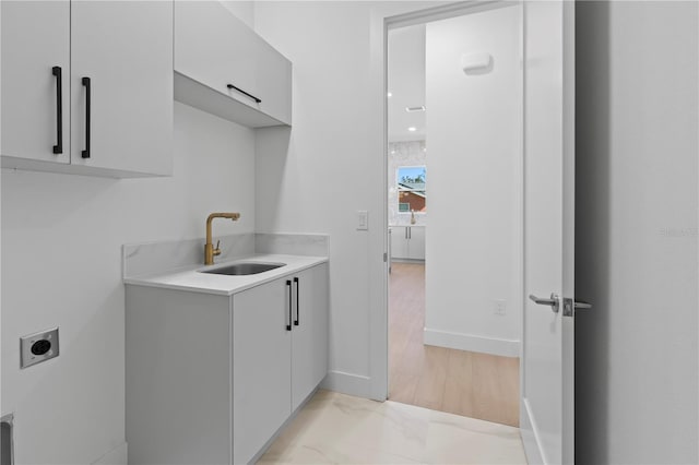 washroom with cabinets, light hardwood / wood-style flooring, electric dryer hookup, and sink