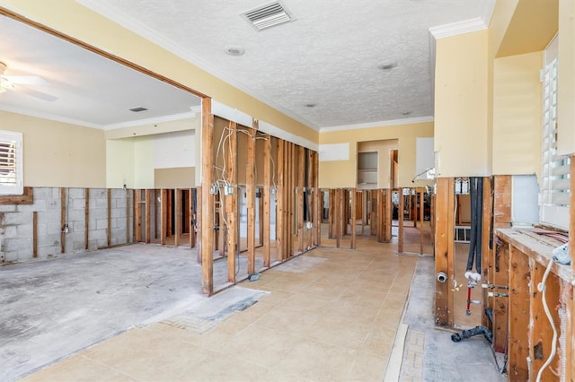 interior space with ceiling fan, ornamental molding, a textured ceiling, and light tile patterned floors