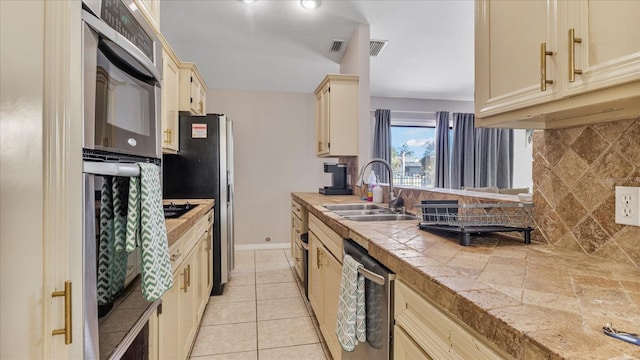 kitchen featuring backsplash, sink, light tile patterned floors, and stainless steel dishwasher