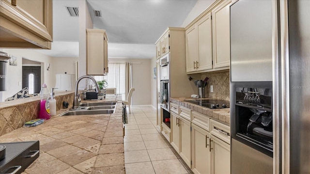 kitchen with cream cabinetry, stainless steel fridge with ice dispenser, sink, and black electric cooktop