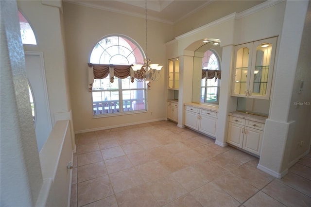 unfurnished dining area featuring a notable chandelier, light tile patterned floors, ornamental molding, and a wealth of natural light