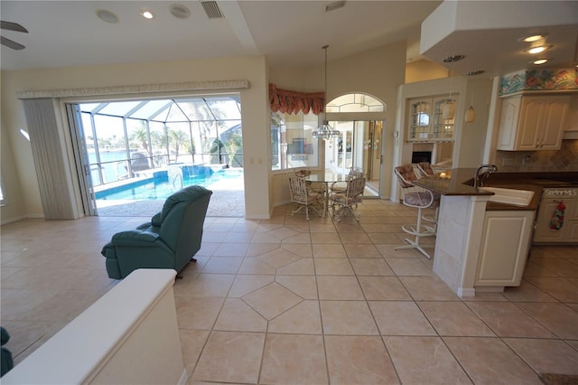 living room featuring light tile patterned floors, vaulted ceiling, ceiling fan, and sink