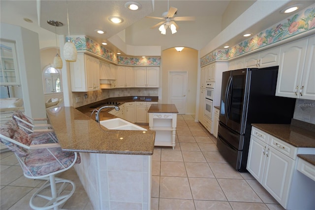 kitchen with pendant lighting, black fridge, sink, light tile patterned floors, and kitchen peninsula