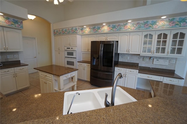 kitchen featuring double oven, stainless steel fridge, white cabinets, and a kitchen island