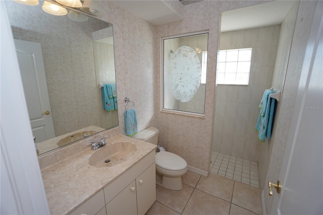 bathroom featuring tile patterned flooring, vanity, toilet, and a tile shower