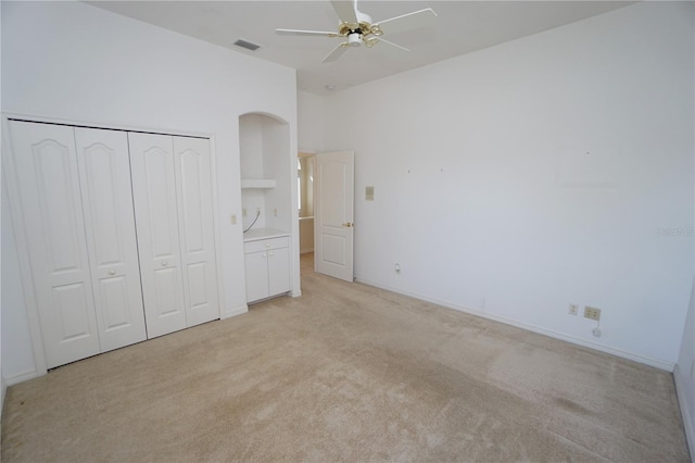 unfurnished bedroom with ceiling fan, a closet, and light colored carpet