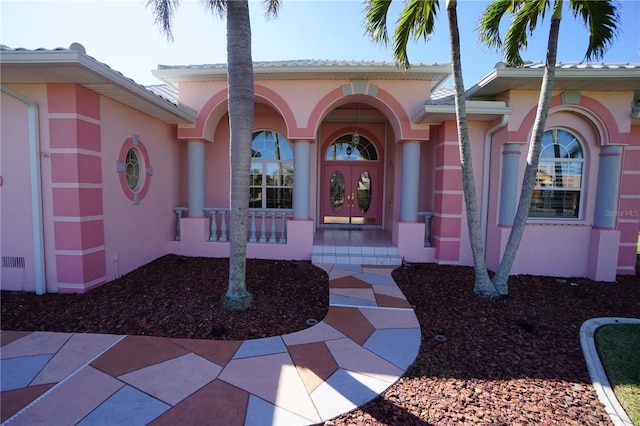 entrance to property with a porch, french doors, and stucco siding