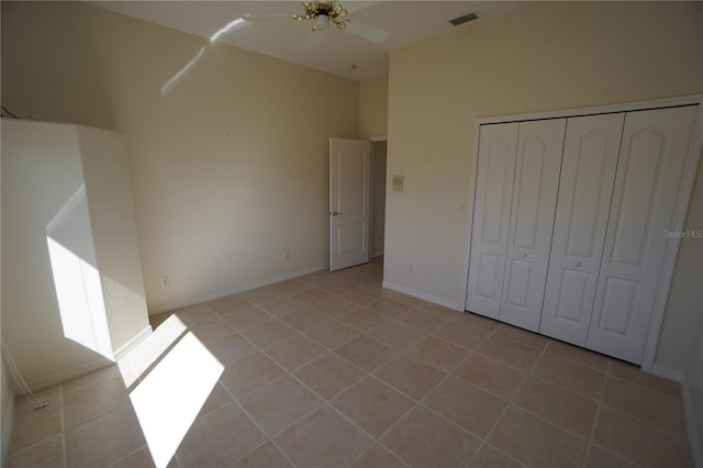 unfurnished bedroom featuring light tile patterned floors, a ceiling fan, visible vents, baseboards, and a closet